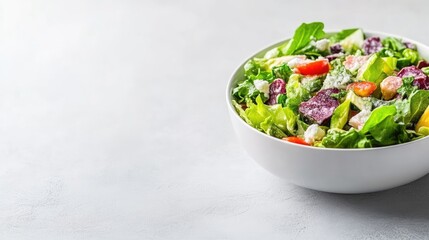 A colorful fresh salad with mixed greens and vegetables in a white bowl, close-up shot on a light grey background, and healthy eating concept.