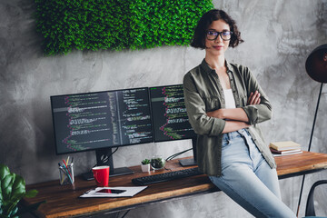 Confident female programmer working from a modern workspace with dual monitors displaying source...