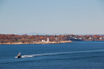 Portland Head Light in Cape Elizabeth, Maine as seen from the Atlantic Ocean on an autumn morning and a coast guard boat passing. An historic 1791 lighthouse still in operation.