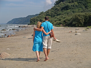 A young couple walks embracing along the shores of the Baltic Sea