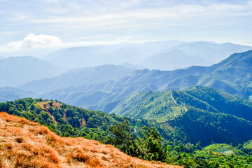 Obraz premium Scenic Mountain Landscape with Blue Sky and Layers of Misty Hills