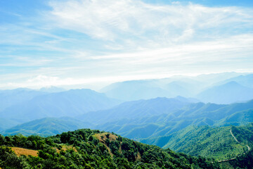 Obraz premium Scenic Mountain Landscape with Blue Sky and Layers of Misty Hills