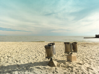Naklejka premium Garbage bins standing on sandy beach promoting cleanliness and environmental protection
