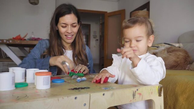 Mother and daughter playing with modeling clay at home