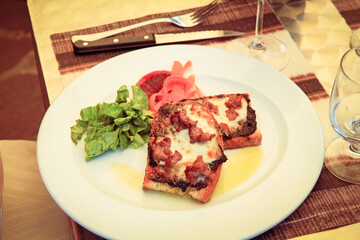 Traditional Italian appetizer bruschetta with cheese and ham on bread.