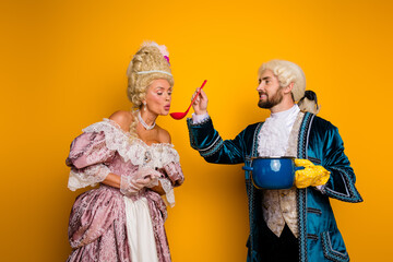 Vintage couple cosplaying royalty from a bygone era on yellow background