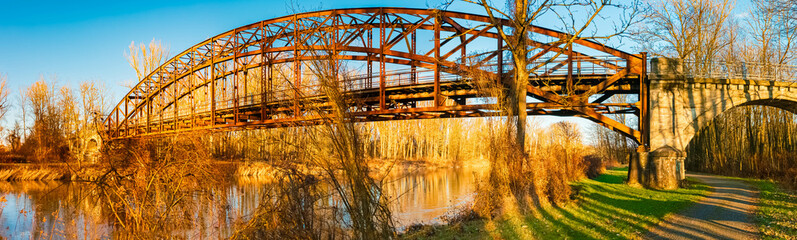 Winter landscape with an old railway bridge and reflections on a sunny evening near Landau an der Isar, Dingolfing-Landau, Bavaria, Germany