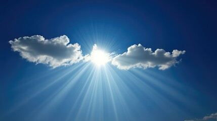 Bright sunbeams piercing through clouds in a clear blue sky