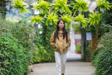 Fototapeta premium Woman walking through green garden pathway