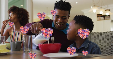 Image of heart icons with flowers over african american family eating breakfast