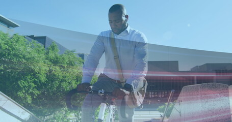 Image of glowing light trails over african american businessman cycling in city