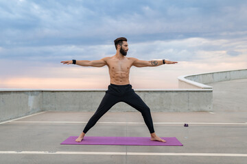 Fototapeta premium attractive hansome man with athletic strong body doing morning yoga asana outdoors