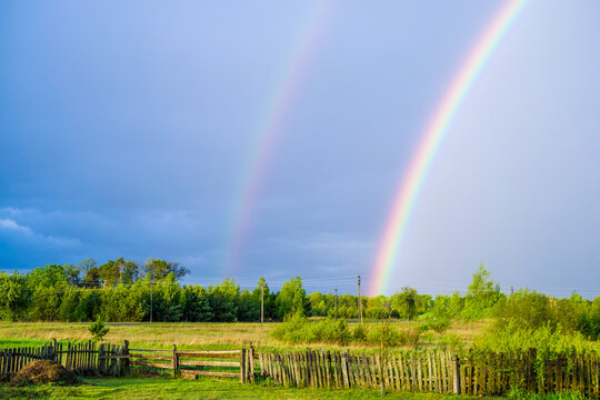 Double rainbow in the sky over a bright spring field after rain in the countryside