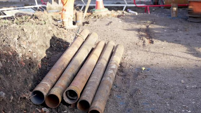 Construction workers place heavy pipes at site 