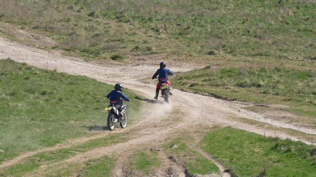 a pair of motor cyclists (bikers) riding their off-road motorbikes