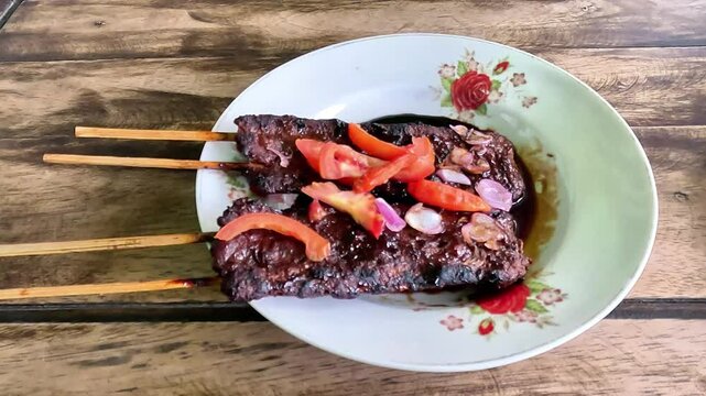 Satay sapi (beef skewered). Served with soy sauce, chili and tomato. The satay is originated in Indonesia