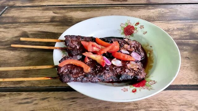 Satay sapi (beef skewered). Served with soy sauce, chili and tomato. The satay is originated in Indonesia