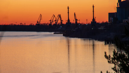 Naklejka premium River port with cranes at sunset