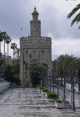 Seville, Spain - Mar 23, 2025: Walking in Seville. Torre del Oro (Gold Tower). Streets, buildings. Lifestyle in the urban area. Cloudy spring day. Selective focus