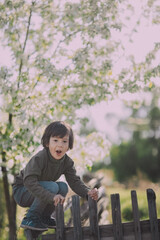 A little boy climbed the fence with a funny expression on his face