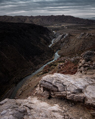 Close-up of stones and dry grass with a river in the background in the mountains.