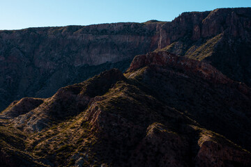 Photograph of dry rocky mountains with lights and shadows marked by sunset.