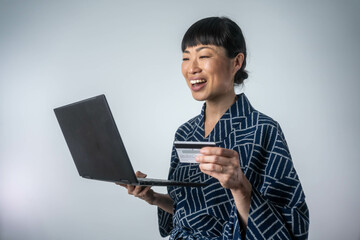 Asian woman in kimono making online payment using laptop for shopping at home. Online shopping concept