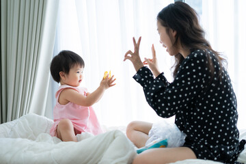 Mom and baby girl is playing together at home