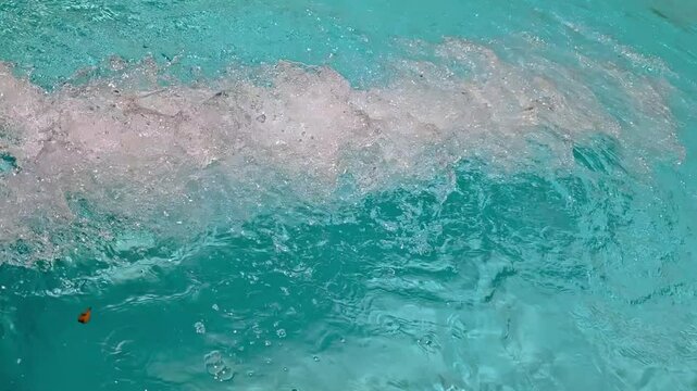 close-up video of turquoise swimming pool water rolling and splashing from the end of a waterslide on an otherwise smooth rippled surface. sunny day fun recreational landscape with sound.