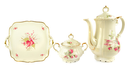 Elegant vintage porcelain coffee pot, porcelain sugar bowl and Vintage plate of unusual shape with gold rim isolated on white background.