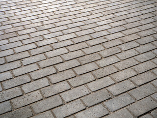 Abstract geometric pavement texture in perspective. Rectangular tiles are laid out in even rows at an angle to the background. Copy space.