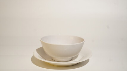 Minimalist shot featuring a pristine white bowl and saucer on light surface