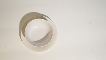 Minimalist Arrangement of White Bowls on a Cream-Colored Surface with Shadow