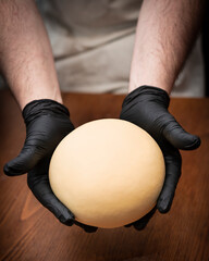 Bollo de masa fresca en manos del maestro pastero, en el obrador artesanal