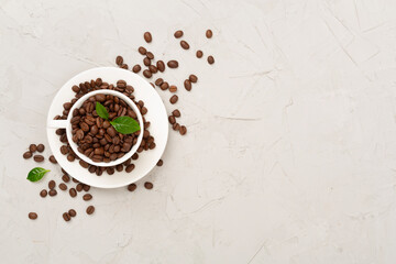 Roasted coffee beans with leaves on concrete background,top view
