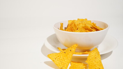 Crispy tortilla chips presentation in a bowl on a bright surface studio shot