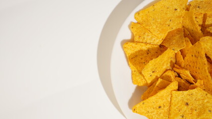 Golden Nacho Chips Arranged on a White Plate against a White Backdrop