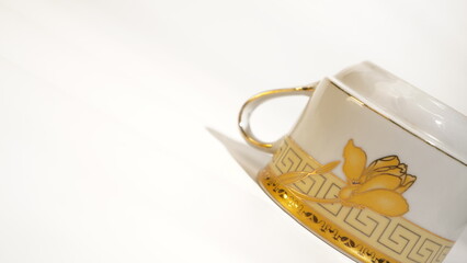 Elegantly Decorated Porcelain Teacup with Gold Accents on a White Surface