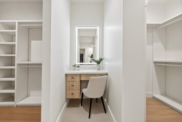 This is a spacious walkin closet that features a vanity, a chair, and a mirror