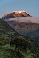 View of snow-capped volcano at sunrise with a cloud under the ice on a Colombian farm, with natural colors in gold. Colombian Andes Nevado del Tolima