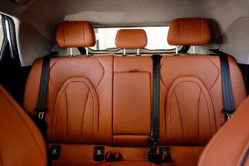 Interior view of a car showcasing brown leather seats with black seat belts.