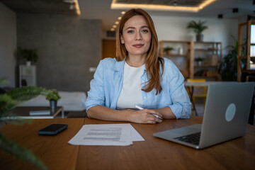 Businesswoman working from home office using laptop and reading documents
