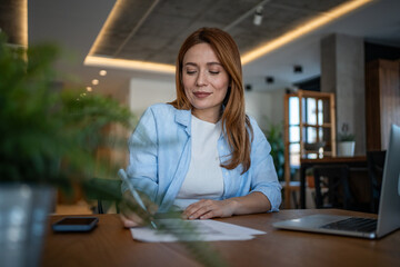 Focused female entrepreneur working on documents at home office