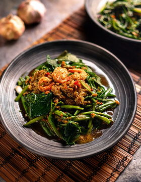 Steaming plates of Malaysian Kangkung Belacan (water spinach stir-fried with shrimp paste) offering a pungent and flavorful vegetable dish.