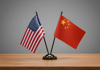american and chinese flags on wooden desk stand with neutral gray background for international relations content
