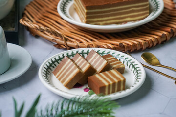 A traditional Indonesian steamed layer cake with alternating vibrant layers, showcasing a soft,...