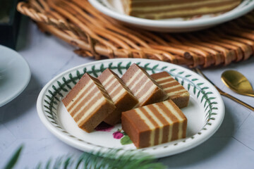A traditional Indonesian steamed layer cake with alternating vibrant layers, showcasing a soft,...