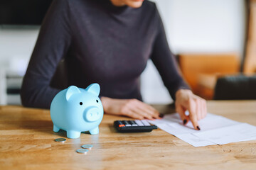 Managing personal finances with a calculator and a piggy bank while reviewing bills and expenses on...