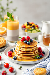 stack of golden pancakes topped with fresh raspberries and blueberries drizzled with sweet syrup