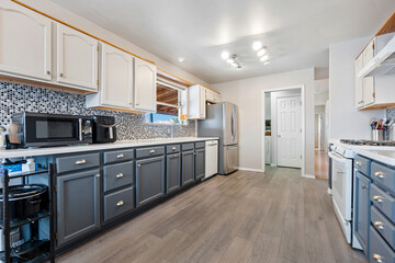 A kitchen with gray cabinets, white countertops, and appliances